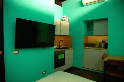 a kitchen with a green wall with a flat screen tv at Riad Campo de' Fiori in Rome