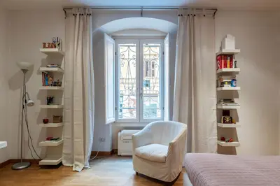a bedroom with a white chair and a window at GuestHost - Suite dell'Emporio in Rome