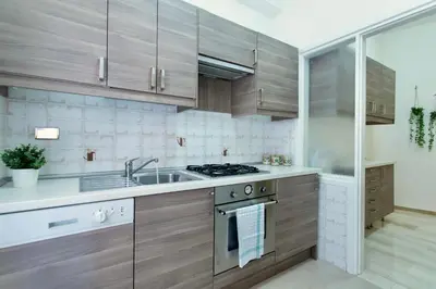 a kitchen with wooden cabinets and a sink and a stove at Elide - Nido d'amore in Ponte Milvio con Balcone in Rome