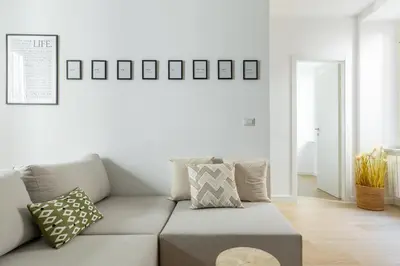 a white living room with a couch and pictures on the wall at iFlat Sunny & Brand New Apartament near Vatican in Rome