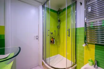 a bathroom with a shower with green and yellow tiles at Casa Sosò... La casa che fa per te! in Rome