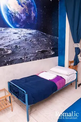 a bed in a room with a mural of the earth at Romatic in Rome