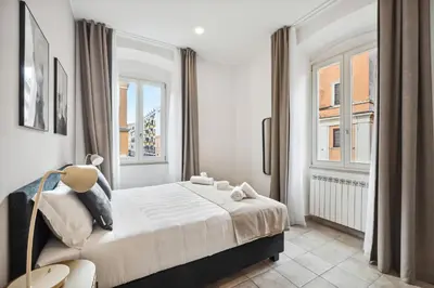 a bedroom with a large bed and two windows at Limehome Rome via dei Reti in Rome