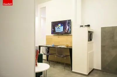 a room with a table and a tv on a wall at GuestHost - Largo Leopardi Modern Apartment in Rome