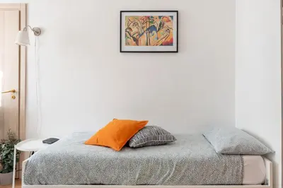 a bed with an orange pillow in a white room at central little basic apartment in Rome