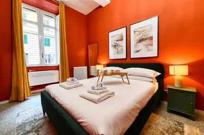a bedroom with orange walls and a bed with towels on it at Elegant oasis among the Vatican and Via del Corso in Rome