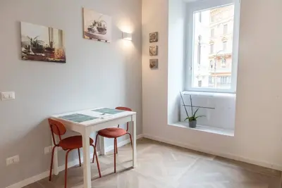 a white table and two chairs in a room with a window at La casa di Jojo al Ghetto in Rome