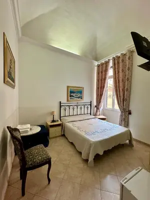 a bedroom with a bed and a chair and a window at Alloggio Turistico in Rome