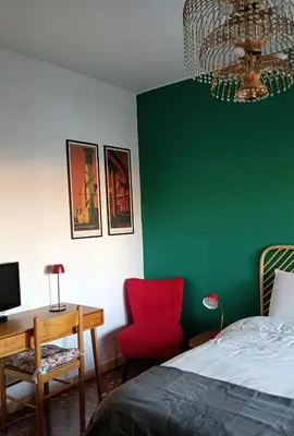 a bedroom with a green wall and a red chair and a desk at Casa Carbone in Rome