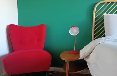 a red chair next to a bed and a table with a lamp at Casa Carbone in Rome