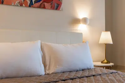 a bedroom with a bed with white pillows and a lamp at Dimora Cardinal Moroni in Rome
