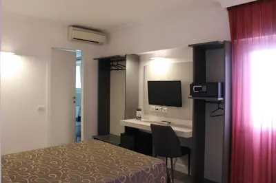 a hotel room with a bed and a desk with a television at Galileo Luxury Terrace Suites Rome in Rome