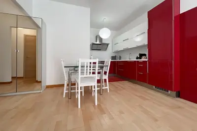 a kitchen with red cabinets and a table with white chairs at La Casa di Roma in Rome