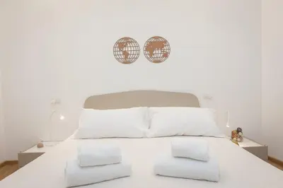 a white bed with white pillows and two clocks on the wall at Colosseum Holidays - Three-Bedroom Apartment in Rome