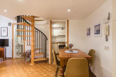 a dining room with a table and chairs and a staircase at Carla Luxury House in Rome