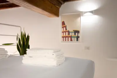 a stack of towels on a white table with a lamp at Trevi Apartment in Rome