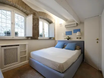 a bedroom with a bed with blue pillows and windows at Antiche Residenze Romane - CAMPO DE' FIORI in Rome
