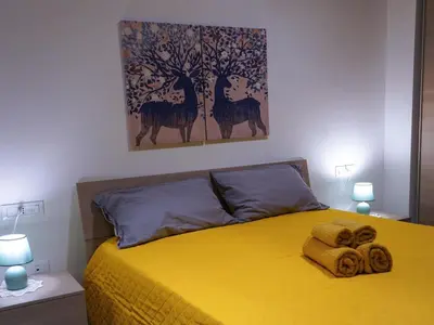 a bedroom with a yellow bed with a painting on the wall at Pandora apartments in Rome
