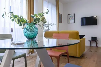 a living room with a glass table with a vase with flowers at Vatican Steps, Suite Mary, Strollingrome in Rome