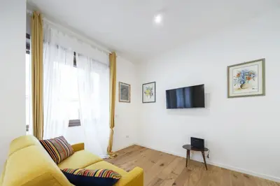 a living room with a yellow couch and a television at Vatican Steps, Suite Mary, Strollingrome in Rome