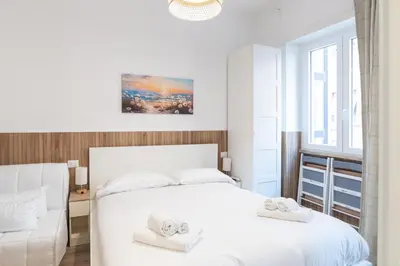 a white bedroom with a bed and a couch at Residence San Paolo in Rome