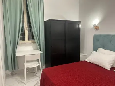 a bedroom with a black cabinet next to a desk at Guesthouse Dahlia Rossa in Rome