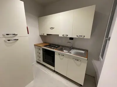 a small kitchen with white cabinets and a sink at Spacious and Bright in Rome
