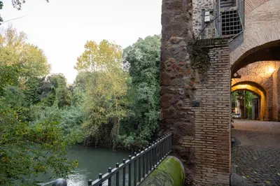 a brick building next to a river with a bridge at Guest house Sempione da Giulio in Rome