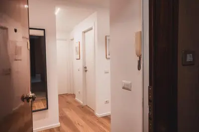 a hallway with white walls and wooden floors and a mirror at MT apartment in Rome