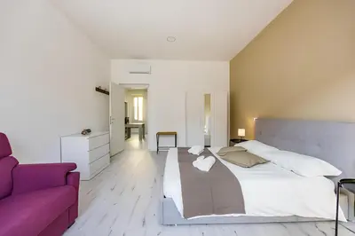 a bedroom with a large bed and a purple couch at 1 Minute from San Pietro - Nicole House in Rome