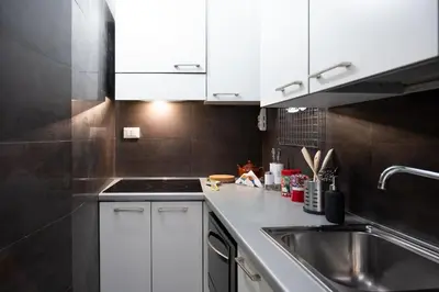 a kitchen with white cabinets and a sink at Casa Bartolomeo - Loft in Trastevere in Rome