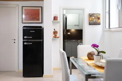 a kitchen with a black refrigerator next to a table at Casa Bartolomeo - Loft in Trastevere in Rome