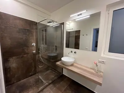 a bathroom with a sink and a glass shower at Paula Petra Vatican Apartments in Rome