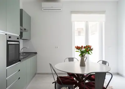 a white kitchen with a table with a vase of flowers at @uRhOME - Luxury Accommodation in Rome