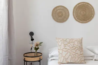 a bed with a pillow and a table with a vase of flowers at iFlat Colosseum Charming Flat in Rome