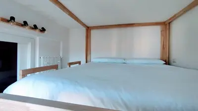 a bedroom with a white bed with a wooden headboard at Attic Roof Oasi Vaticana in Rome