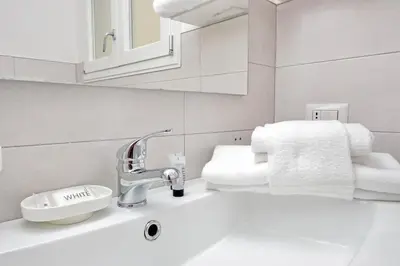 a white bathroom with a sink and towels at YCH-Confortevole appartamento vicino Ponte Milvio in Rome