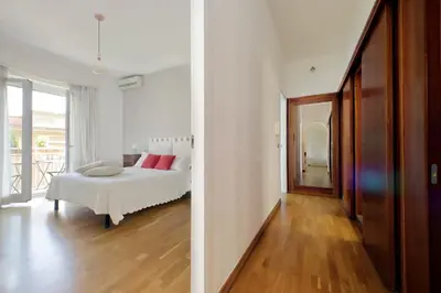 a white bedroom with a bed and a wooden floor at YCH-Confortevole appartamento vicino Ponte Milvio in Rome
