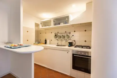 a small kitchen with white cabinets and a sink at Emerald - in the heart of Trastevere in Rome