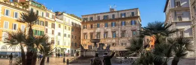 a group of buildings with palm trees and a fountain at Emerald - in the heart of Trastevere in Rome