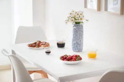 a white table with two plates of food and a vase with flowers at Esclusivo Appartamento di design (metro Tiburtina) in Rome