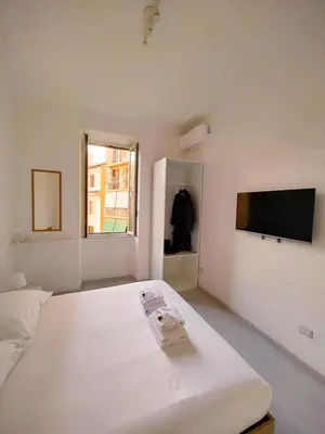 a white bedroom with a bed and a flat screen tv at ViviRome - 2 Bedrooms Apartment - San Giovanni in Rome