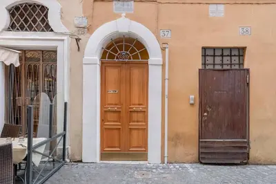 a wooden door next to a building with an arch at Elegante rifugio in centro storico Roma tra Piazza del Popolo e Piazza di Spagna in Rome