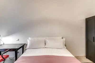 a bed with white pillows in a room with a desk at Montebello Apartments79 in Rome