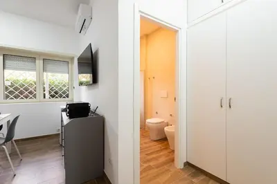 a bathroom with a toilet and a room with white walls at Aurelia Deluxe Suites in Rome