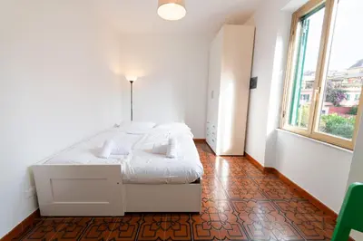 a bedroom with a white bed and a large window at Casa di Marianna e Vittorio al Gemelli in Rome