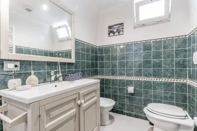 a green tiled bathroom with a toilet and a sink at La Rosa Dei Papi in Rome