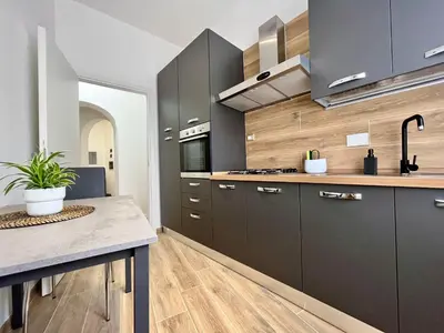 a kitchen with black cabinets and a table at PyramidHouse Rome - Apartment 100mq with View - 2km from the Colosseum in Rome