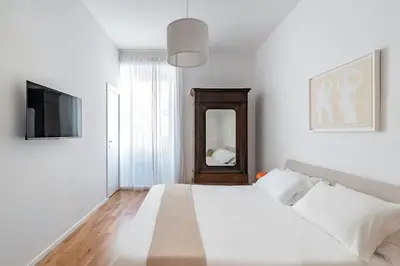 a white bedroom with a bed and a mirror at GIULIANA Boutique Apartment in Rome