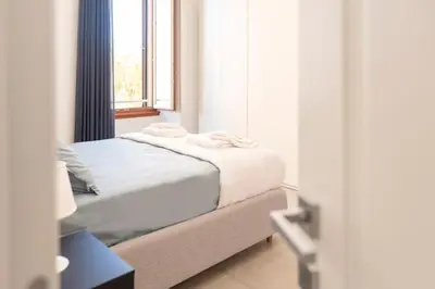 a bedroom with a bed with white sheets and a window at Élite Vatican Refuge in Rome